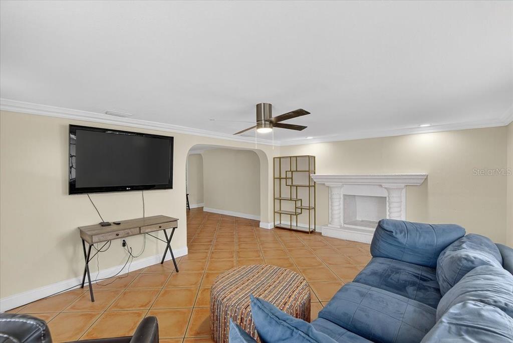 A living room features a blue sofa, a fireplace, a television, and tile flooring — 4515 W NORTH STREET, TAMPA, FL