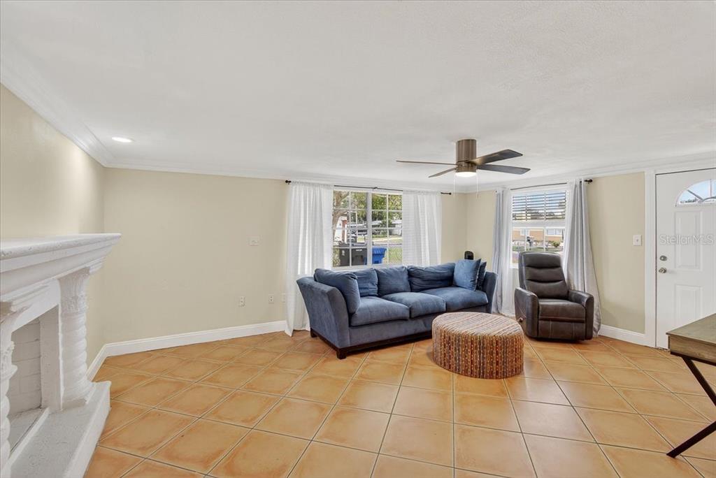 A living room features tile flooring, a blue sofa, a recliner, and a white fireplace — 4515 W NORTH STREET, TAMPA, FL