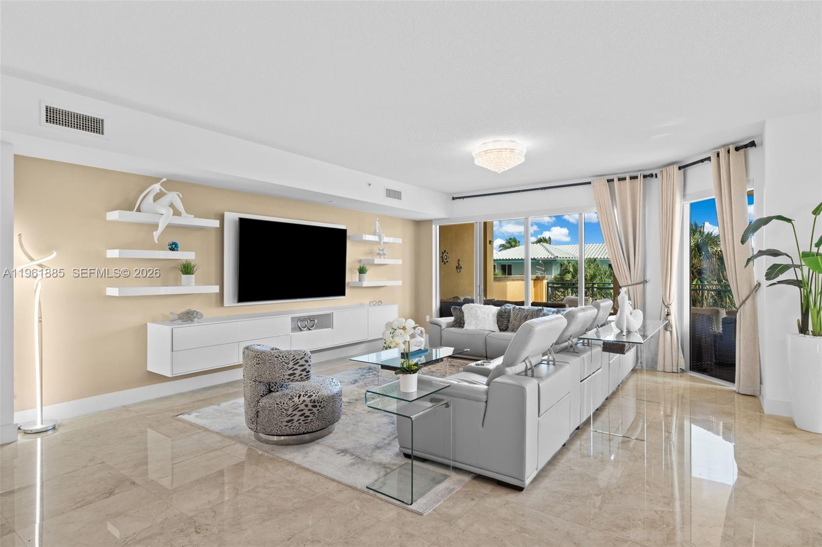 A modern living room features a large television, white floating shelves, and a grey sectional — 3415 N Ocean Dr # 204, Hollywood FL 33019, HOLLYWOOD, FL