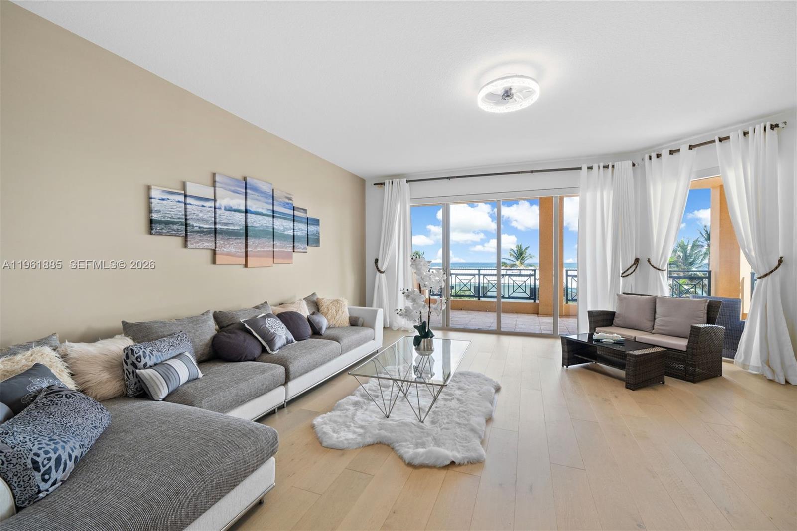 A living room features a sectional sofa, a glass coffee table, and a balcony view — 3415 N Ocean Dr # 204, Hollywood FL 33019, HOLLYWOOD, FL