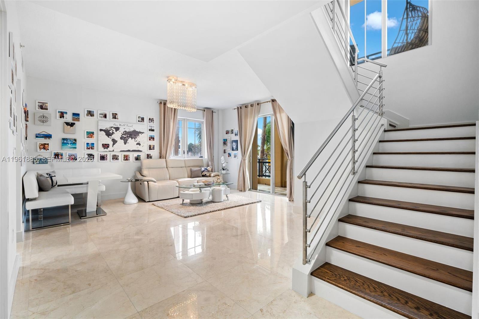 A bright living room features a staircase, tile flooring, and a wall of framed photos — 3415 N Ocean Dr # 204, Hollywood FL 33019, HOLLYWOOD, FL
