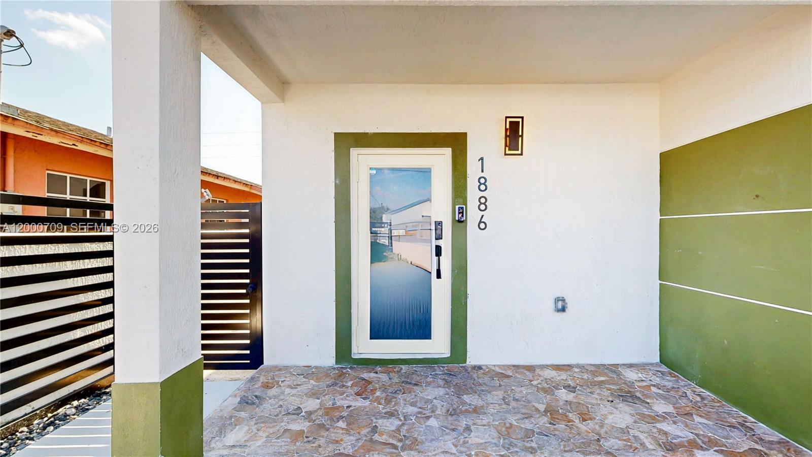 A front entrance features a glass-paneled door, stone flooring, and olive green accent walls — 1886 NW 68th St, Miami FL 33147, MIAMI, FL