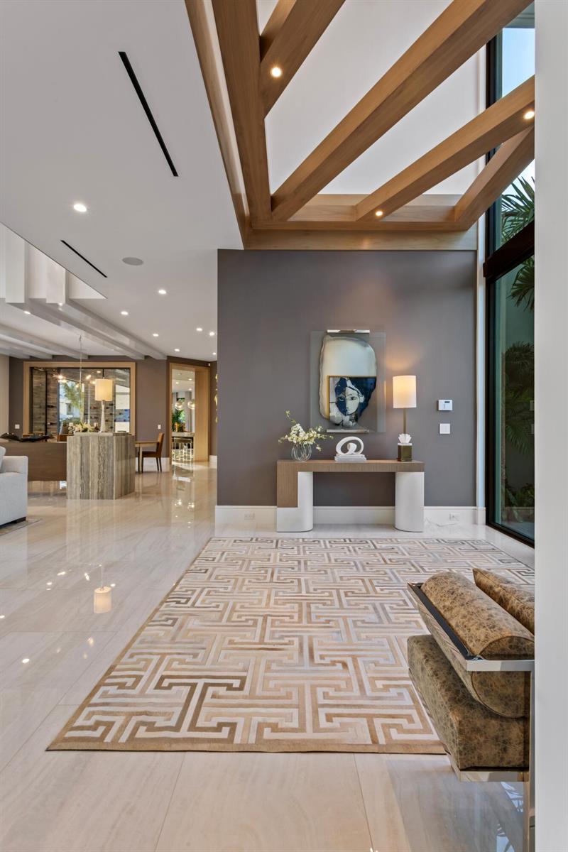 A modern entryway features a geometric rug, a console table, and exposed wooden ceiling beams — 4111 Ibis Point Circle, Boca Raton FL 33431, BOCA RATON, FL