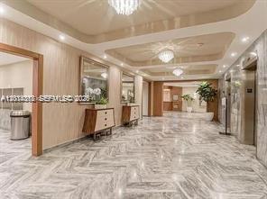 A modern building lobby features marble floors, recessed lighting, and a wood-paneled elevator area — 5401 Collins Ave # 932, Miami Beach FL 33140, MIAMI BEACH, FL