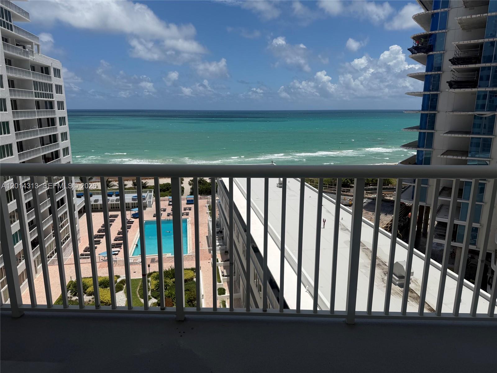 A balcony view overlooks a swimming pool, a flat-roofed building, and the ocean — 5401 Collins Ave # 932, Miami Beach FL 33140, MIAMI BEACH, FL