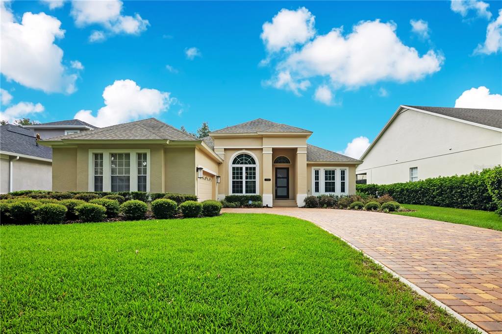 A single-story house with a tan exterior, arched window, and a brick paver driveway — 11462 CLAYMONT CIRCLE, WINDERMERE, FL
