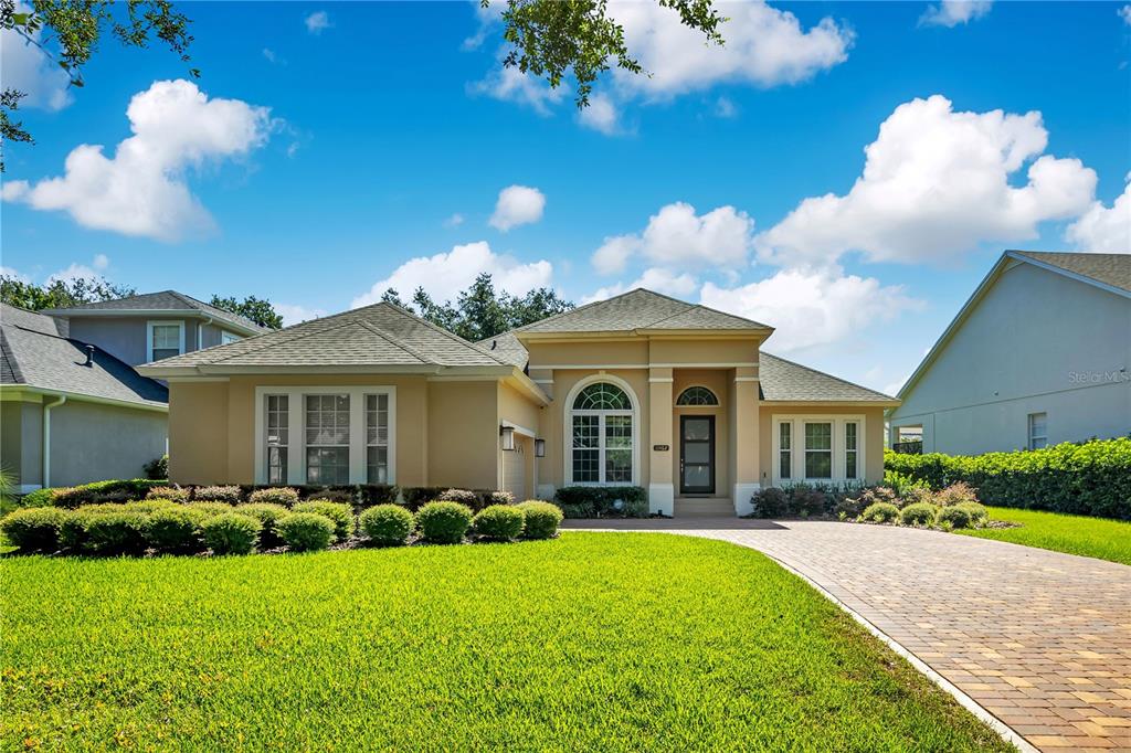 A single-story tan house with a brick paver driveway and a manicured front lawn — 11462 CLAYMONT CIRCLE, WINDERMERE, FL