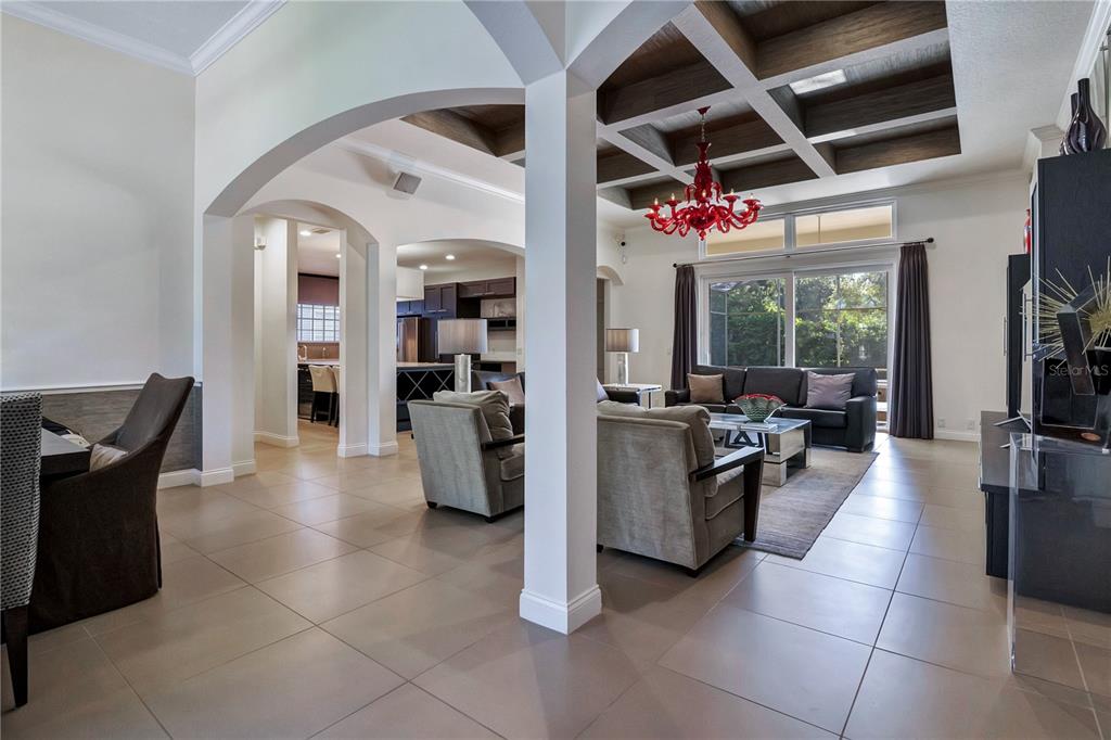 A living room features a coffered ceiling, a red chandelier, and arched architectural openings — 11462 CLAYMONT CIRCLE, WINDERMERE, FL