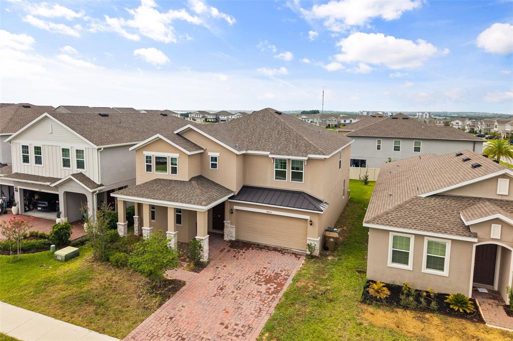 An aerial view shows a two-story tan house with a brick driveway and shingled roof — 14452 CRESTAVISTA AVENUE, CLERMONT, FL