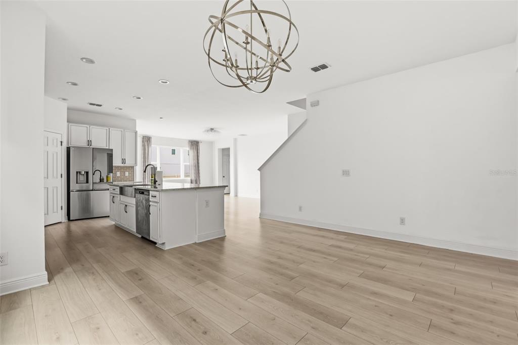 An open-concept kitchen with white cabinetry and an island overlooks a spacious living area — 14452 CRESTAVISTA AVENUE, CLERMONT, FL
