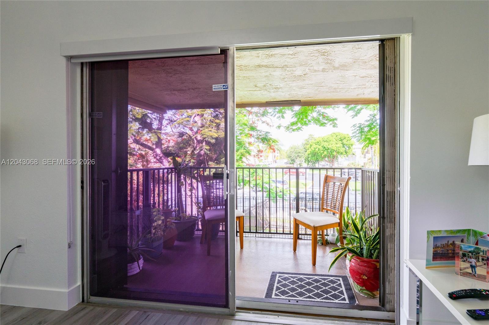 A sliding glass door opens to a balcony with chairs, potted plants, and metal railings — 10501 SW 108th Ave # 209, Miami FL 33176, MIAMI, FL