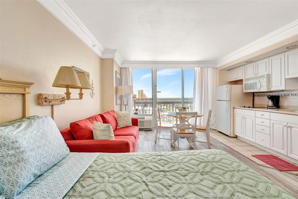 A studio apartment features a bed, red sofa, dining set, and a small kitchen area — 2700 N ATLANTIC AVENUE UNIT 1006, DAYTONA BEACH, FL