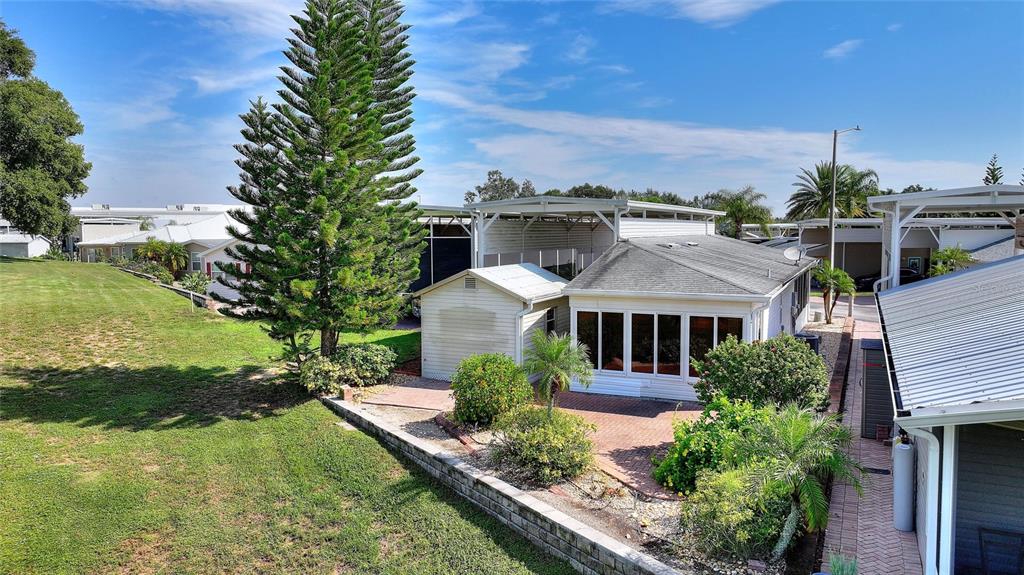 An exterior view of a house with a brick patio, a shed, and a tall pine — 1144 DEER CREEK BOULEVARD, DAVENPORT, FL