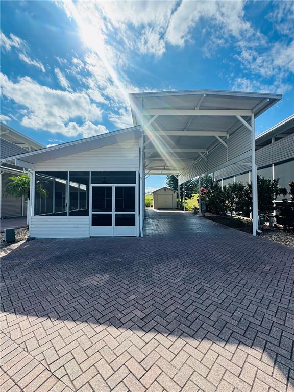 A paved driveway leads to a covered carport and an attached screened-in porch — 1144 DEER CREEK BOULEVARD, DAVENPORT, FL
