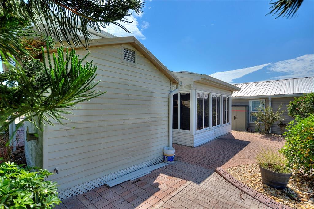 A beige house exterior features a brick patio, a sunroom, and a small storage shed — 1144 DEER CREEK BOULEVARD, DAVENPORT, FL