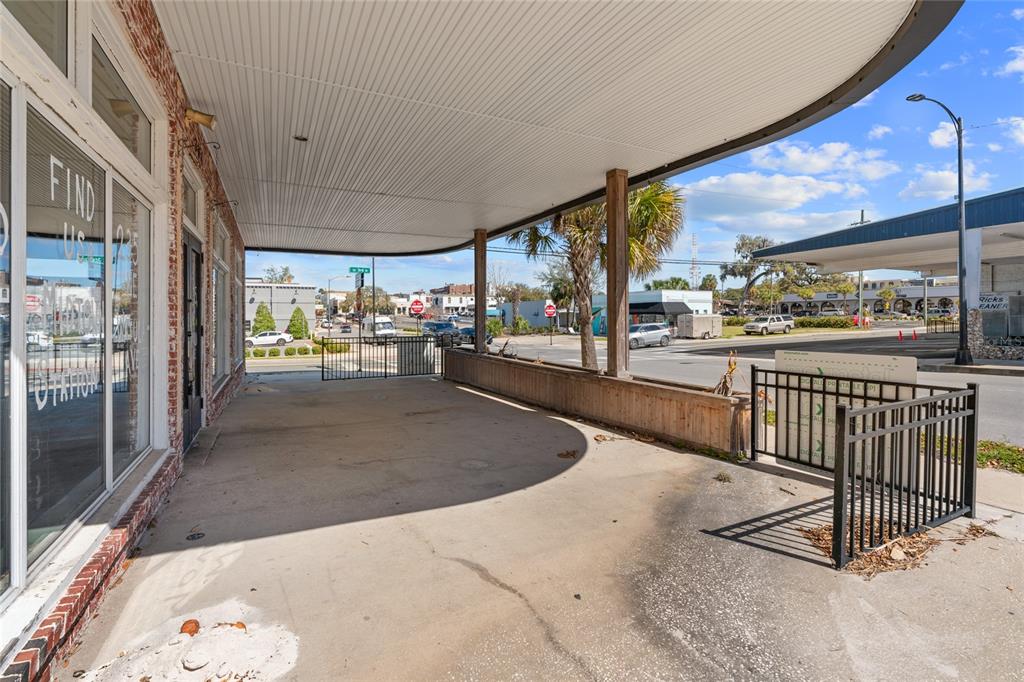 A covered concrete patio with a brick building facade and a black metal railing — 304 S MAGNOLIA AVENUE, OCALA, FL