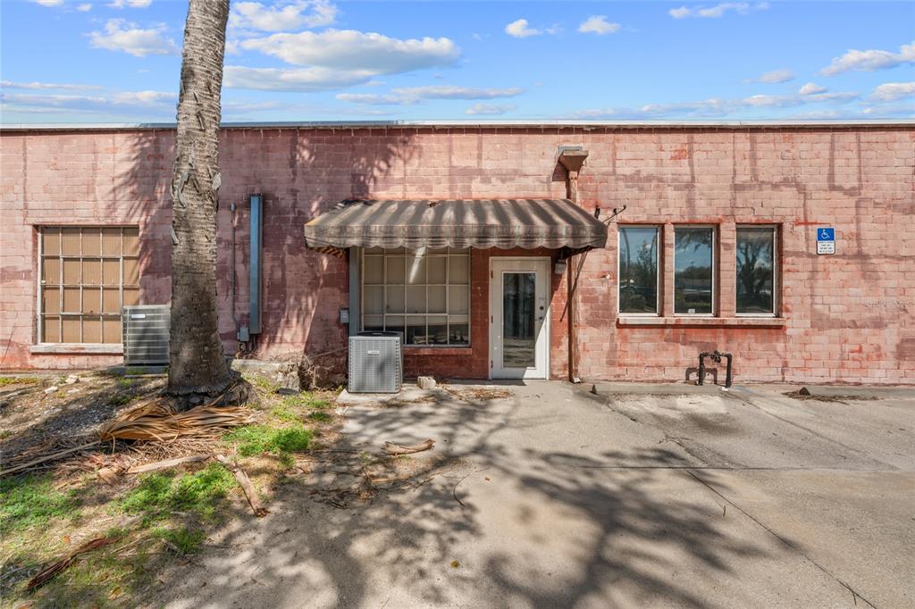 The exterior of a weathered brick commercial building features a striped awning and a door — 304 S MAGNOLIA AVENUE, OCALA, FL