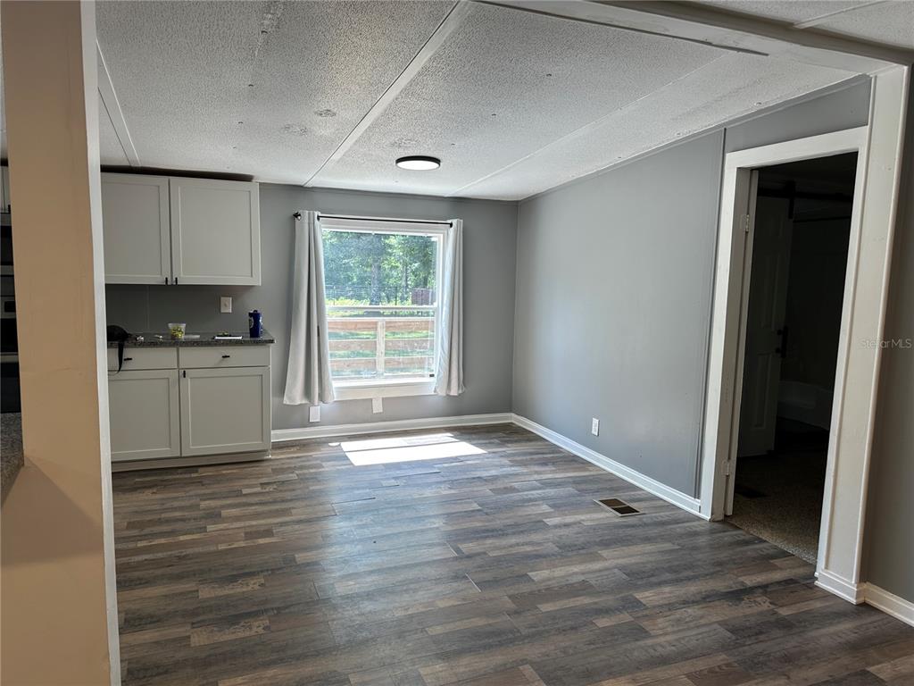 A kitchen area features light gray cabinets, wood-look flooring, and a window overlooking a yard — 11882 SW 58TH STREET, WEBSTER, FL