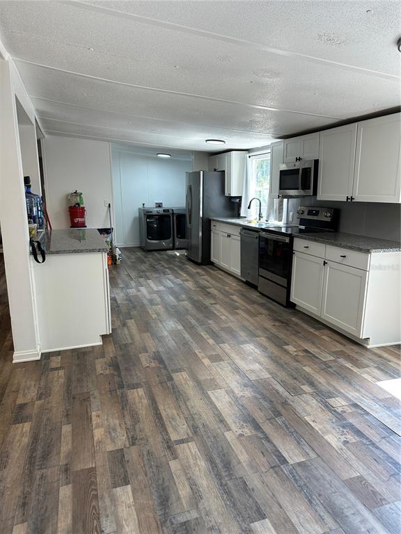 A kitchen features white cabinets, stainless steel appliances, and wood-look flooring — 11882 SW 58TH STREET, WEBSTER, FL