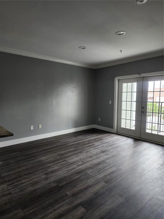 An empty room features gray walls, dark wood-look flooring, and glass French doors leading outside — 206 E SOUTH STREET UNIT 6034, ORLANDO, FL