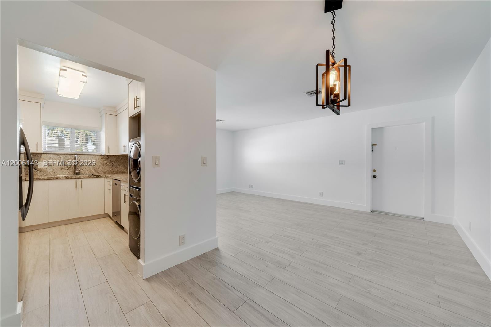 A kitchen with white cabinets and a laundry area opens into a bright living space — 8048 SW 80 AVE # 8048, Miami FL 33143, MIAMI, FL