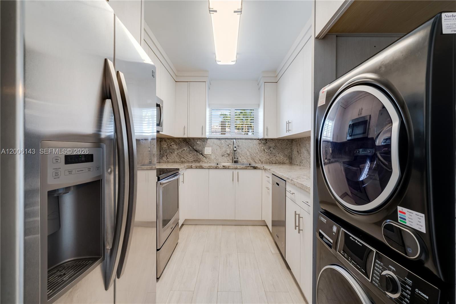 A galley kitchen features white cabinets, granite countertops, stainless steel appliances, and a stacked washer-dryer — 8048 SW 80 AVE # 8048, Miami FL 33143, MIAMI, FL