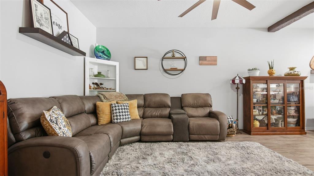 A living room features a brown sectional sofa, a shag rug, and a wooden display cabinet — 212 EVERTREE LOOP, SANFORD, FL