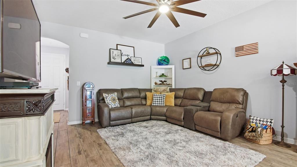 A living room features a brown sectional sofa, a shag rug, and a ceiling fan — 212 EVERTREE LOOP, SANFORD, FL
