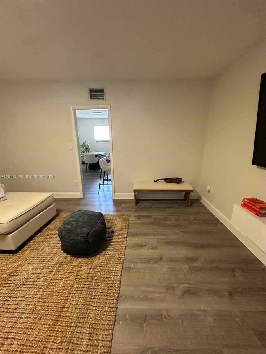 A living room features light wood-look flooring, a jute rug, and a wooden bench — 6805 SW 88th St # 18, Pinecrest FL 33156, PINECREST, FL