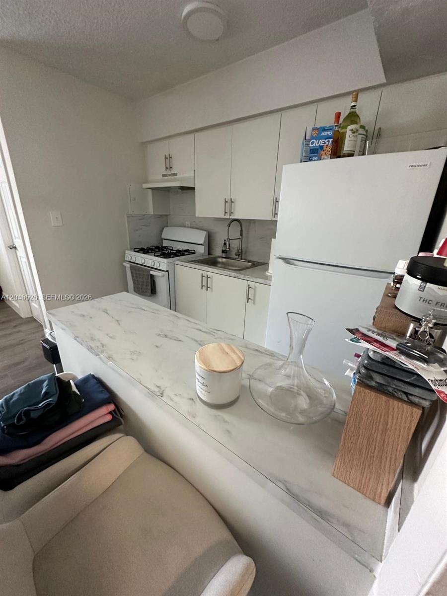 A kitchen features white cabinets, a marble-look countertop, and a white refrigerator — 6805 SW 88th St # 18, Pinecrest FL 33156, PINECREST, FL