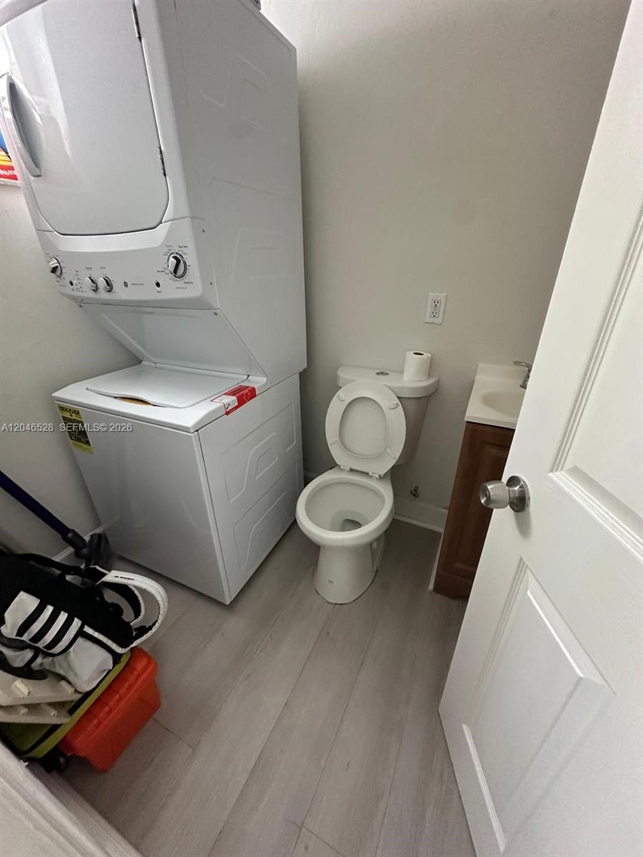 A small laundry room contains a stacked washer and dryer next to a toilet — 6805 SW 88th St # 18, Pinecrest FL 33156, PINECREST, FL