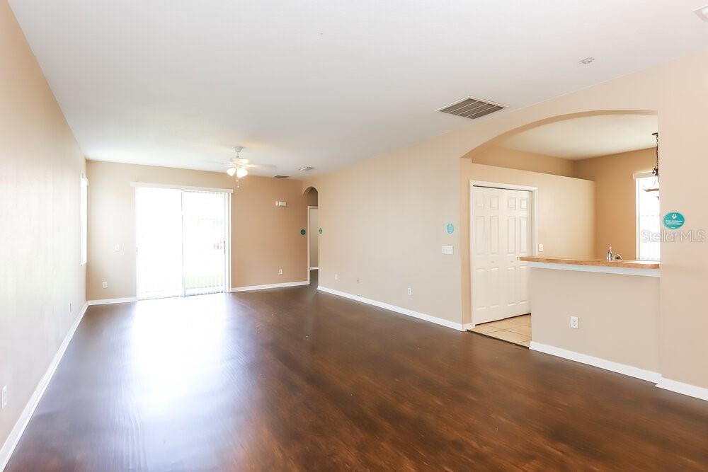 An open-concept living area features dark wood-look flooring, tan walls, and a kitchen breakfast bar — 10330 AVELAR RIDGE DRIVE, RIVERVIEW, FL