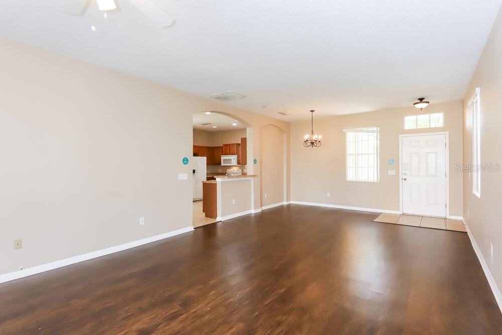 A spacious living room with dark wood flooring leads to an open kitchen area — 10330 AVELAR RIDGE DRIVE, RIVERVIEW, FL