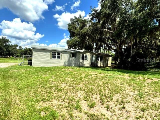 A single-story manufactured home with light siding, green shutters, and a small wooden front staircase — 5411 PLESS ROAD, PLANT CITY, FL