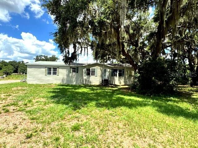 A single-story manufactured home sits on a grassy lot beneath a large, moss-draped oak tree — 5411 PLESS ROAD, PLANT CITY, FL