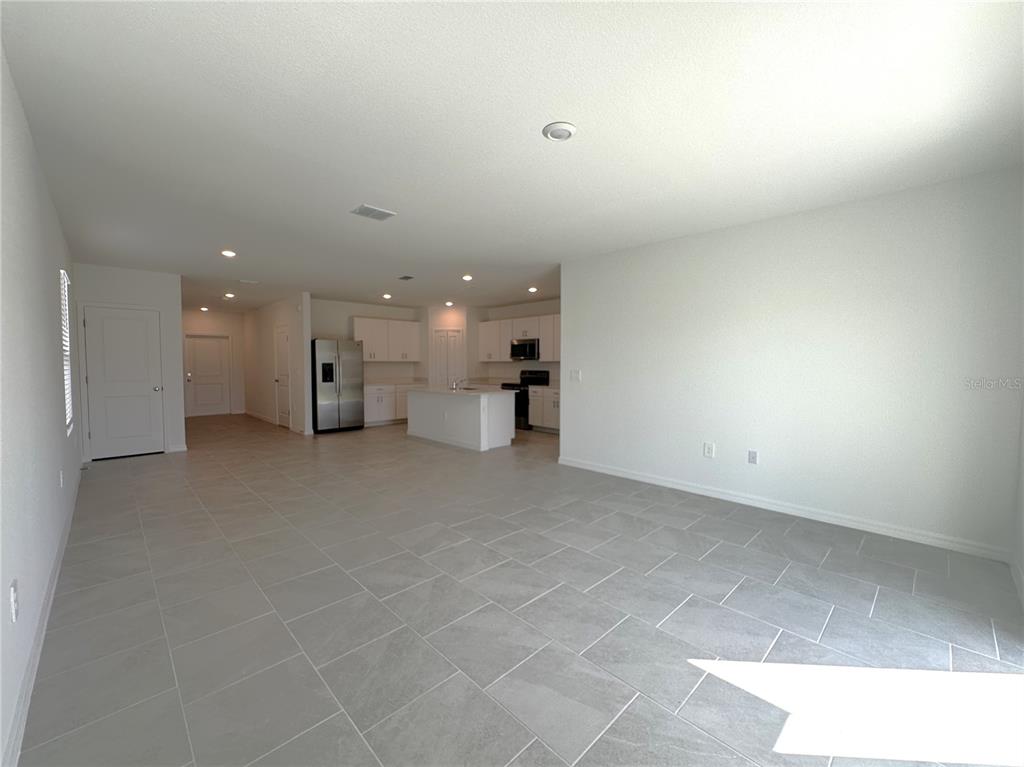 An open-concept living area features light gray tile flooring and a kitchen with white cabinetry — 11847 CLOVERLY LANE, PUNTA GORDA, FL