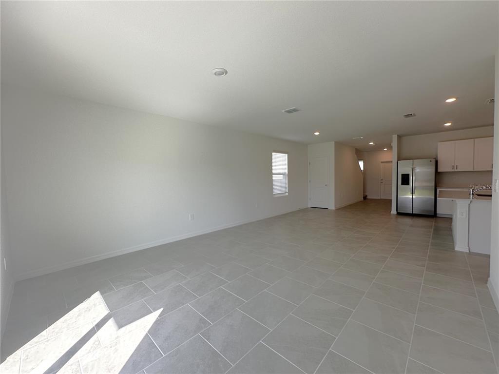 An open-concept living area features light-colored tile flooring, white walls, and a kitchen with stainless appliances — 11847 CLOVERLY LANE, PUNTA GORDA, FL
