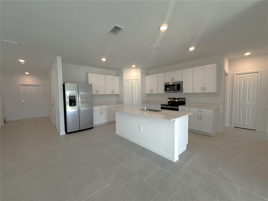 A kitchen features white cabinets, stainless steel appliances, a center island, and light tile flooring — 11847 CLOVERLY LANE, PUNTA GORDA, FL