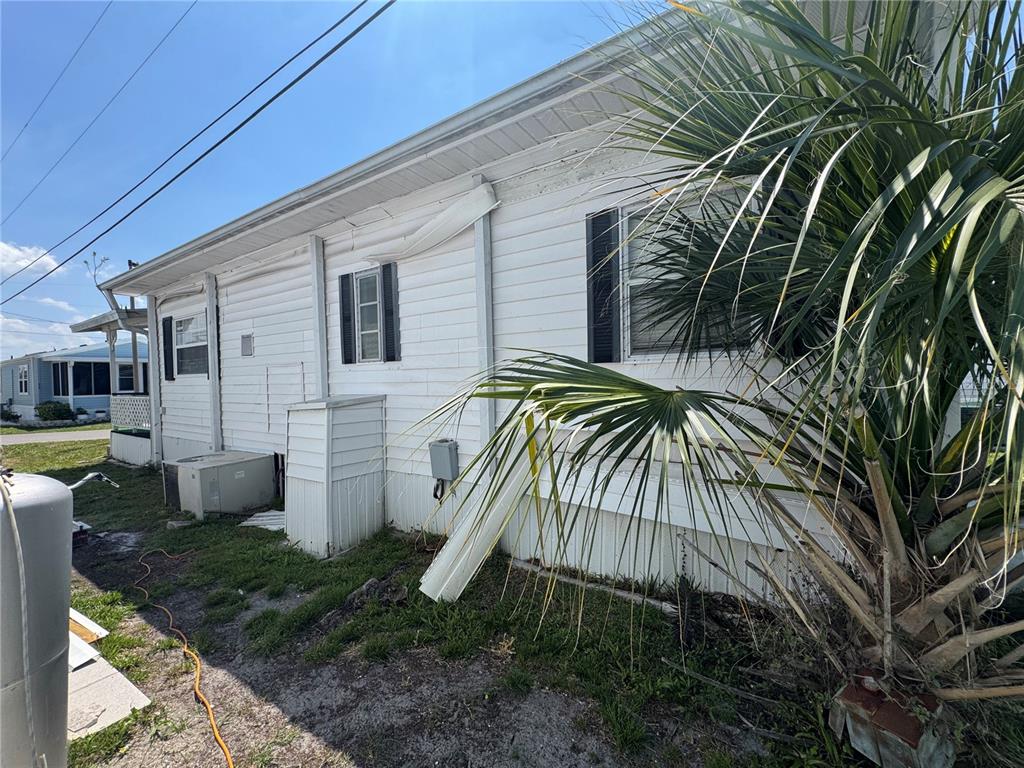 The exterior of a white mobile home features a palm tree and utility equipment — 2049 CHAMPION STREET, SARASOTA, FL