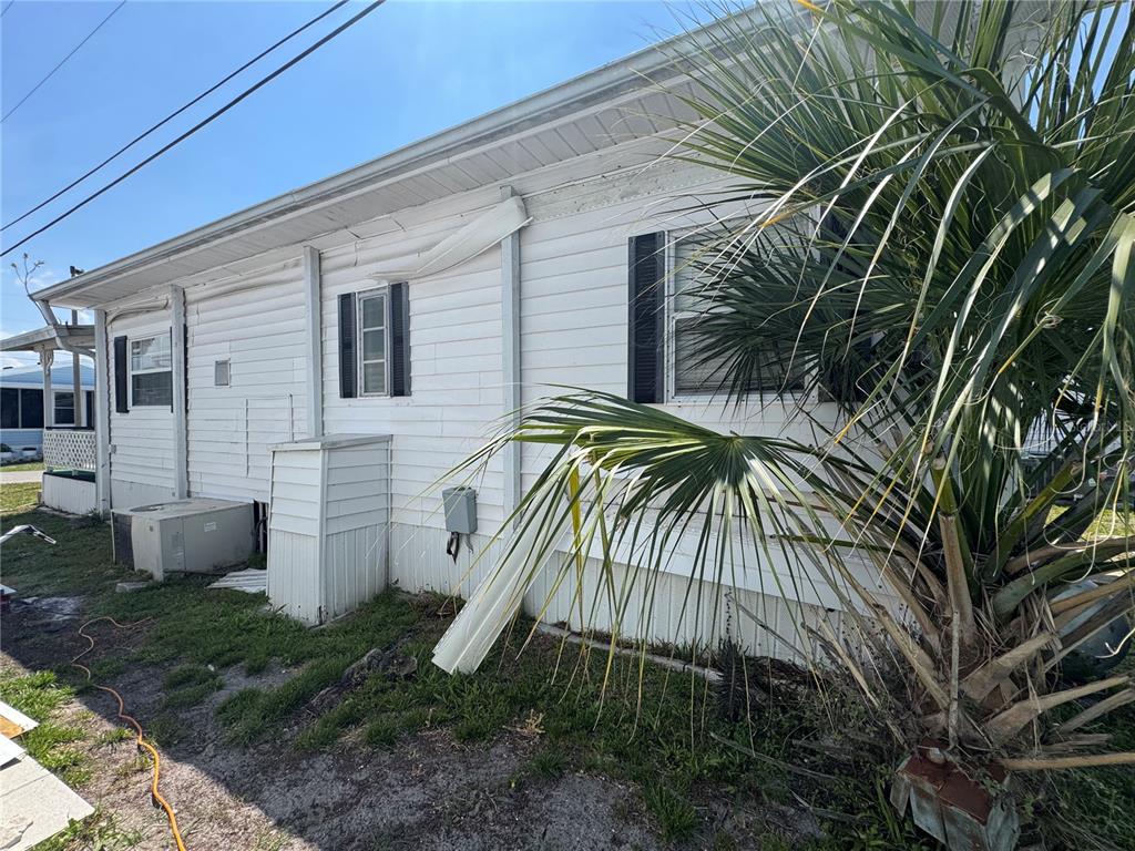 The exterior side of a white mobile home features a palm tree and utility equipment — 2049 CHAMPION STREET, SARASOTA, FL