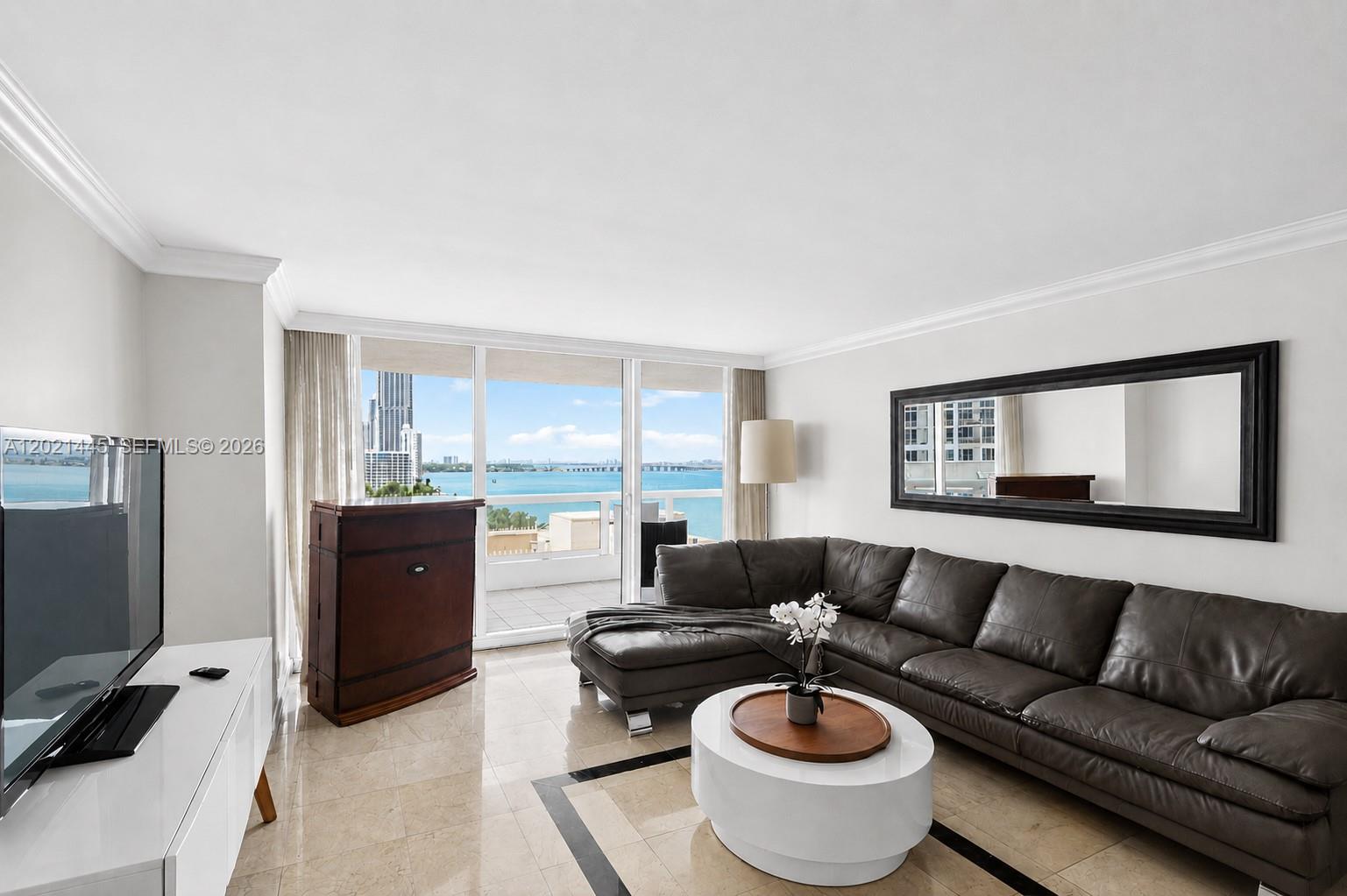 A living room features a dark leather sectional, white coffee table, and floor-to-ceiling balcony windows — 1717 N Bayshore Dr # 1437, Miami FL 33132, MIAMI, FL