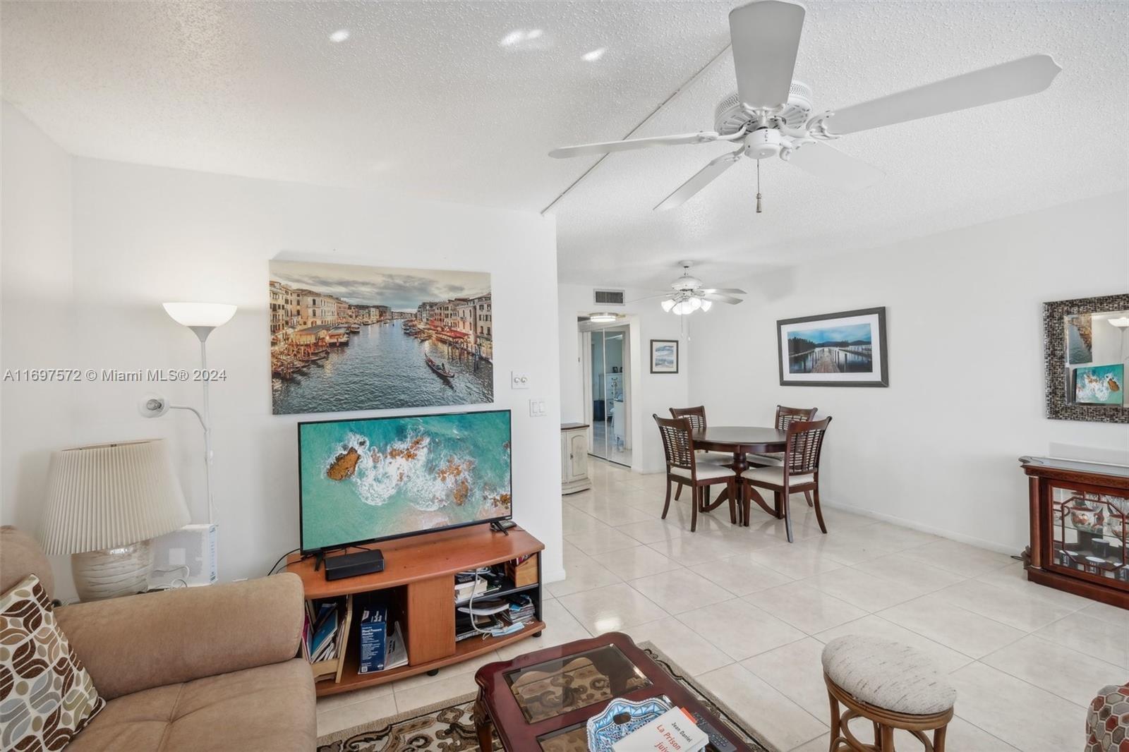 A living and dining area with tile floors, ceiling fans, and a television console — 3014 Oakridge A # 3014, Deerfield Beach FL 33442, DEERFIELD BEACH, FL