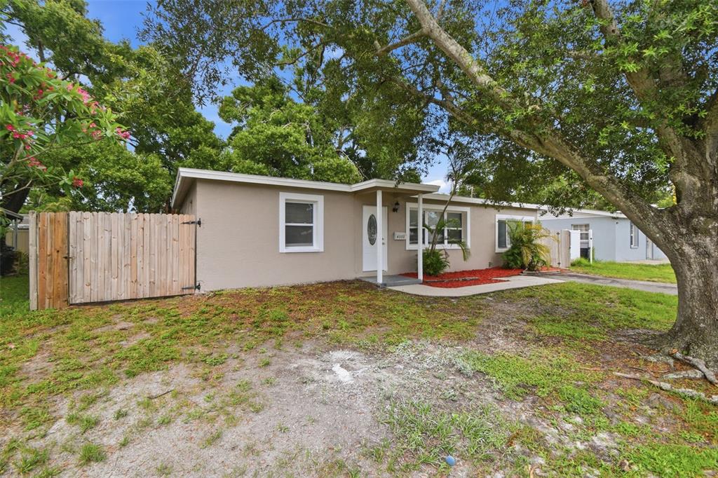 A single-story house with a beige exterior, a white front door, and a wooden fence — 8331 55TH STREET N, PINELLAS PARK, FL
