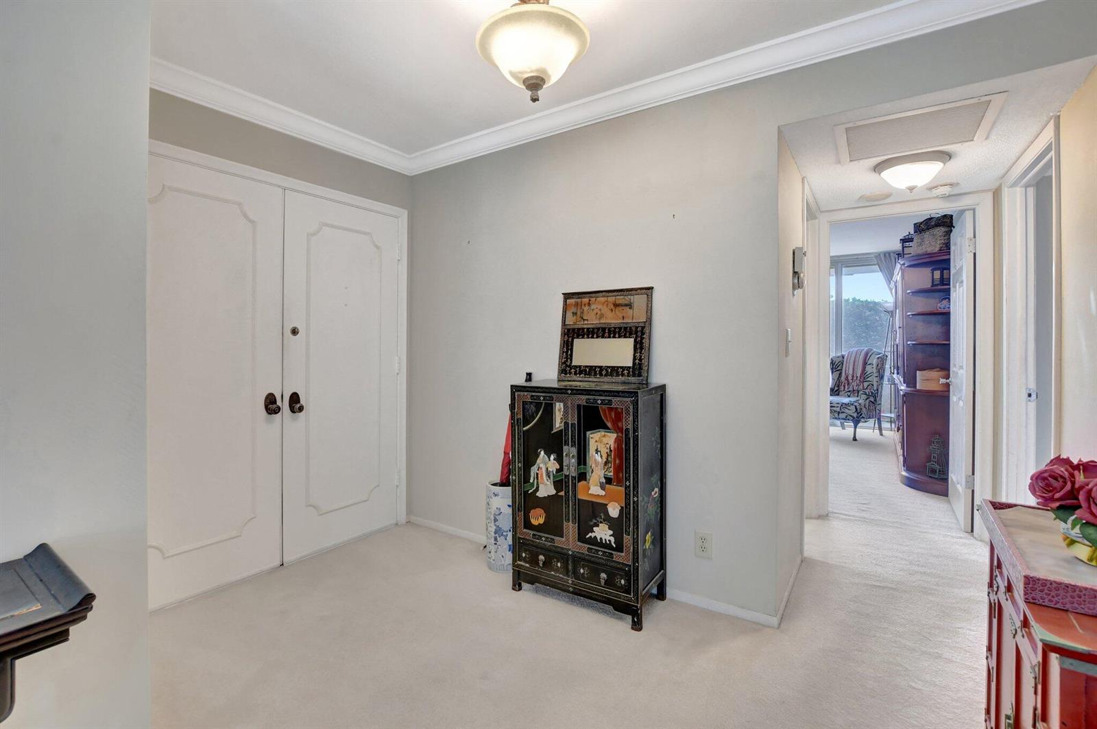 A foyer with white carpet, double doors, and an ornate black cabinet against a wall — 1180 S Ocean Boulevard # 2e, Boca Raton FL 33432, BOCA RATON, FL