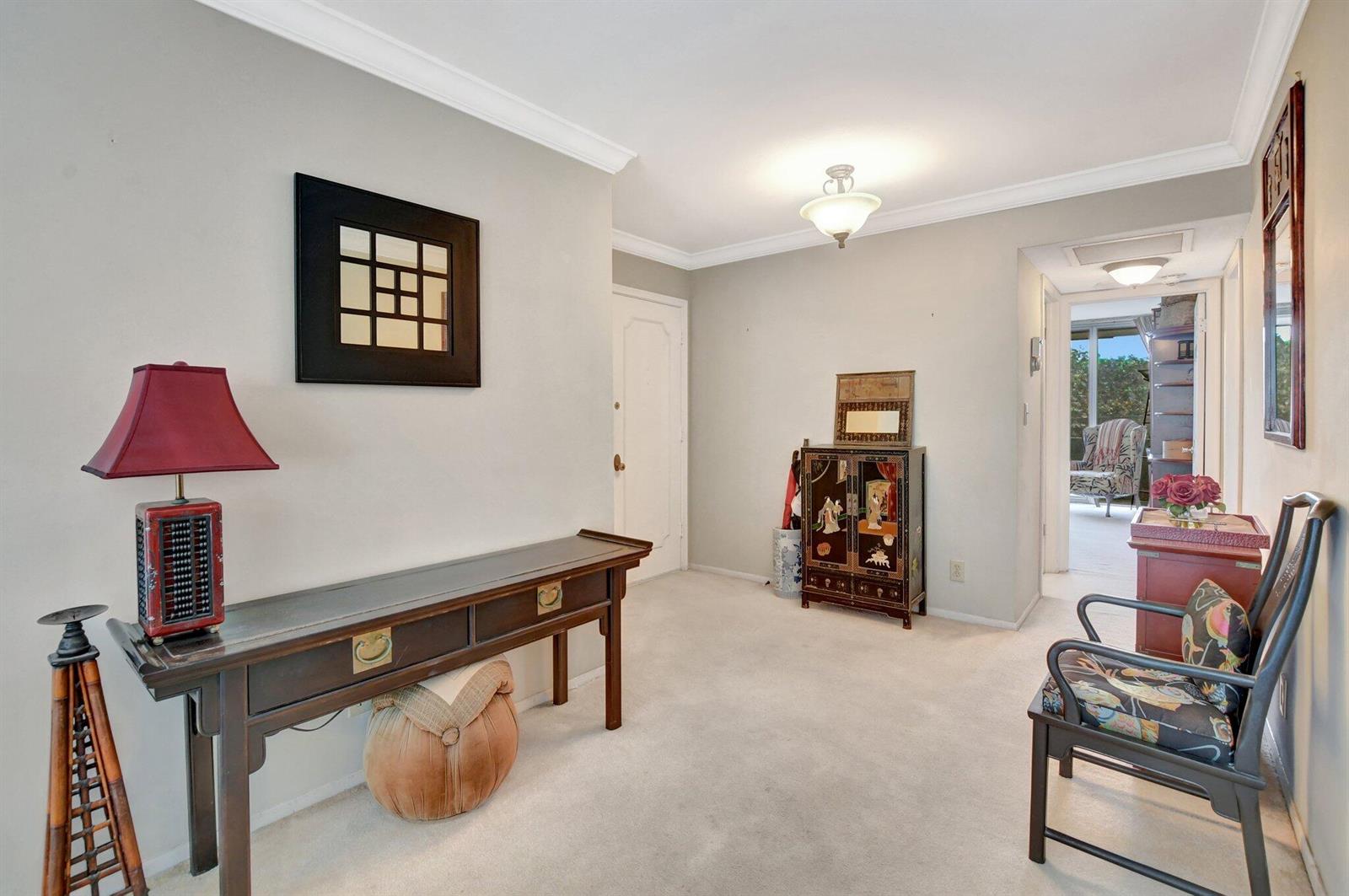 An entryway features a long wooden console table, a small cabinet, and a wooden chair — 1180 S Ocean Boulevard # 2e, Boca Raton FL 33432, BOCA RATON, FL