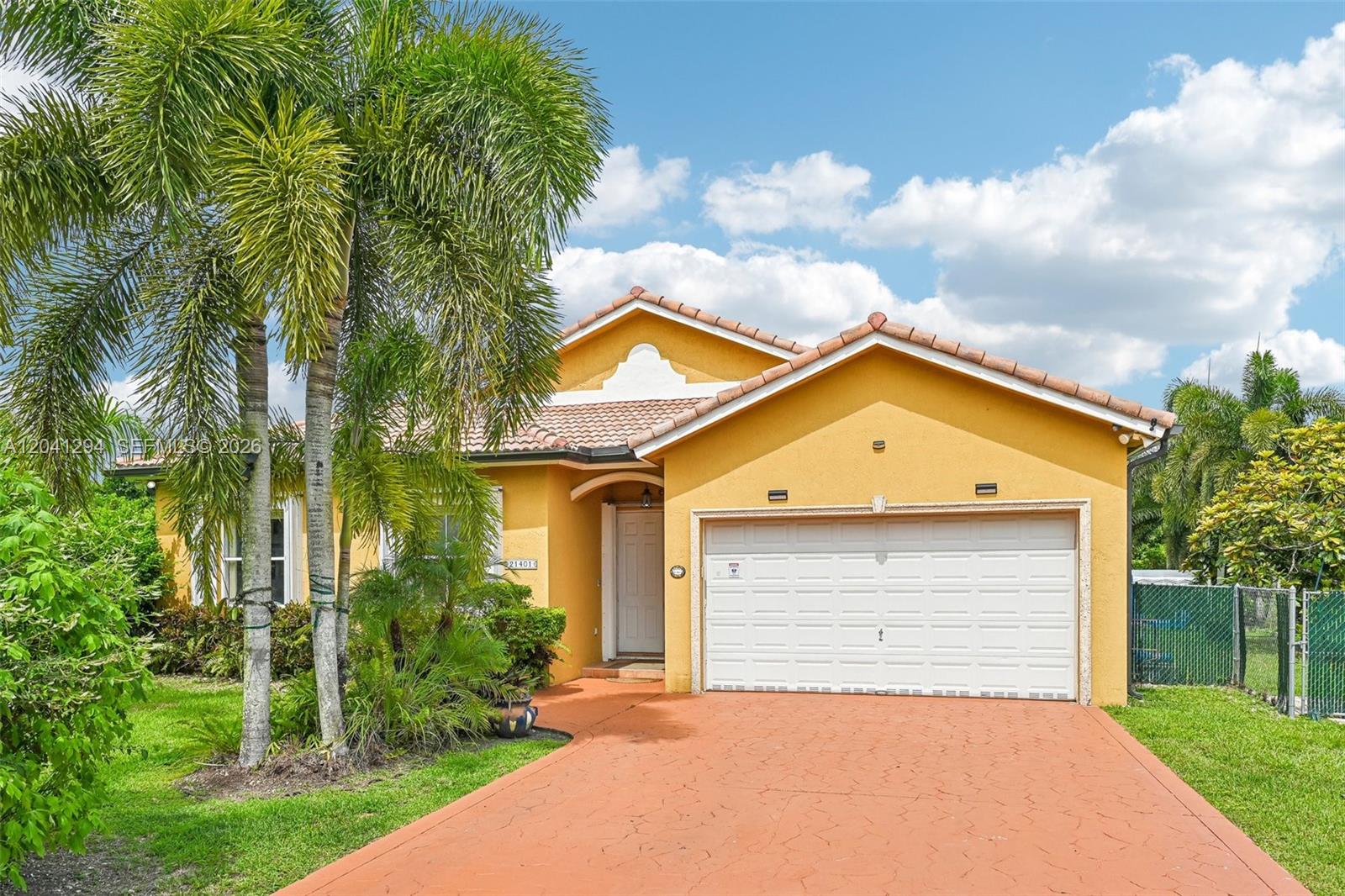 A yellow single-story house with a tile roof, a two-car garage, and palm trees — 21401 SW 187th Ave, Miami FL 33187, MIAMI, FL
