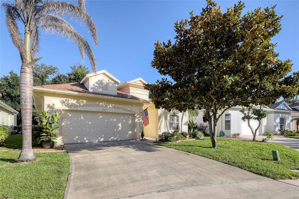 A beige single-story house with a two-car garage, a palm tree, and a large tree — 565 GREENLEAF LANE, TITUSVILLE, FL