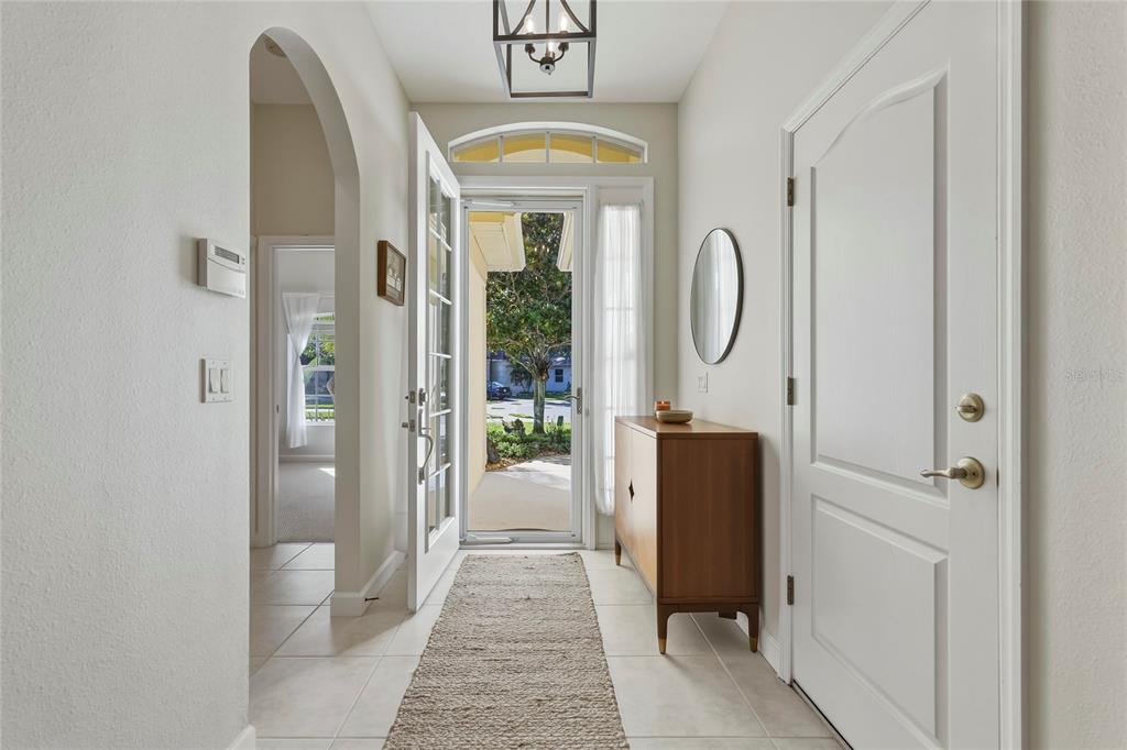 A bright entryway features tile flooring, a wooden console table, and an arched doorway — 565 GREENLEAF LANE, TITUSVILLE, FL