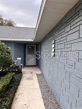 A concrete walkway leads to the front entrance of a house with gray stone siding — 9020 SW 91ST TERRACE, OCALA, FL