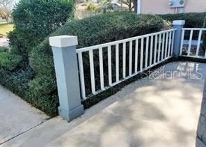 A concrete porch features a white railing and a blue pillar next to a hedge — 9020 SW 91ST TERRACE, OCALA, FL